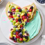 Die Mermaid Tail Fruit Pizza ist ein köstliches Dessert, verziert mit bunten Früchten auf Zuckerkekskruste.