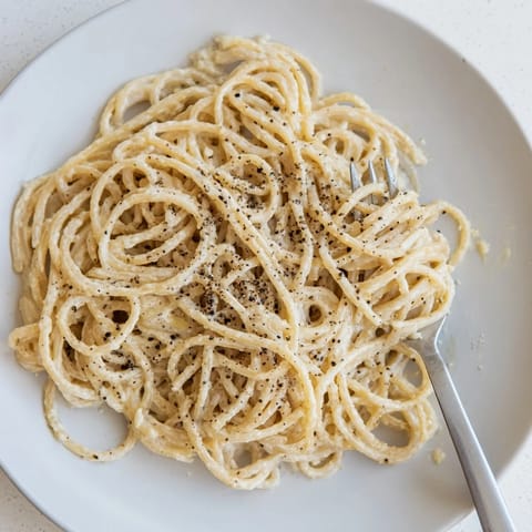 Ein Teller Spaghetti Cacio e Pepe, umrandet von würziger schwarzer Pfefferfrucht.