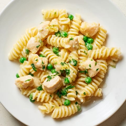 Tender chicken pieces nestled among rotini pasta and sweet green peas in a glossy garlic butter sauce.