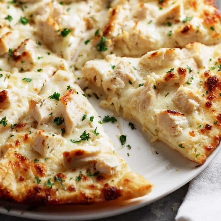 Saftiges Hähnchen auf heißer Chicken Alfredo Pizza mit knusprigem Rand, Parmesan und Mozzarella, perfekt für ein sättigendes Abendessen.
