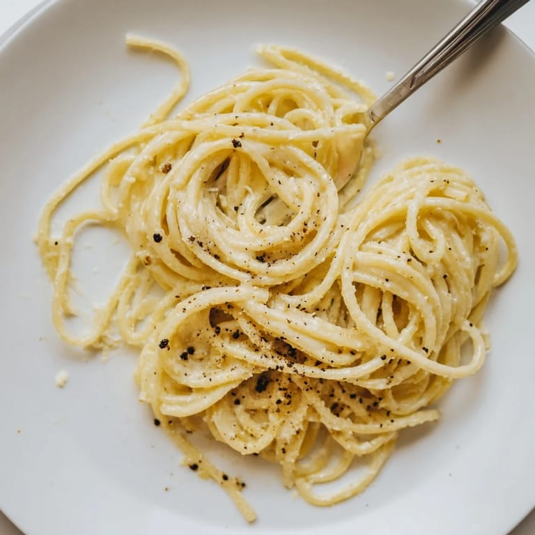 Dampf steigt über einem zubereiteten Gericht aus Spaghetti Cacio e Pepe auf.
