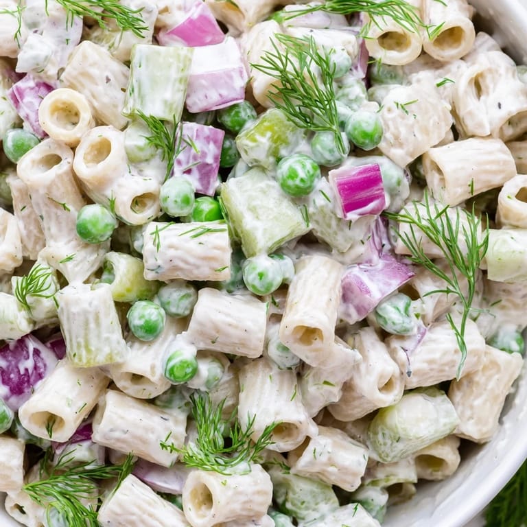 Frisch angerichteter Dill-Pickle-Pasta-Salat für Picknicks mit spiralförmigen Nudeln, Gurkenwürfeln und grünen Erbsen in Creme-Dressing.