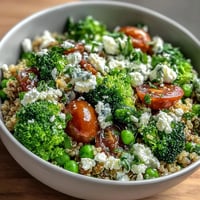 Ein bunter Getreideschüssel mit Quinoa, Brokkoli, Erbsen und cremigem Feta, perfekt für ein gesundes Mittag- oder Abendessen.