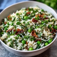 Leuchtendes Frühlingserbsen-Minz-Reis-Pilaf mit frischen Kräutern und Zitronenzesten.  